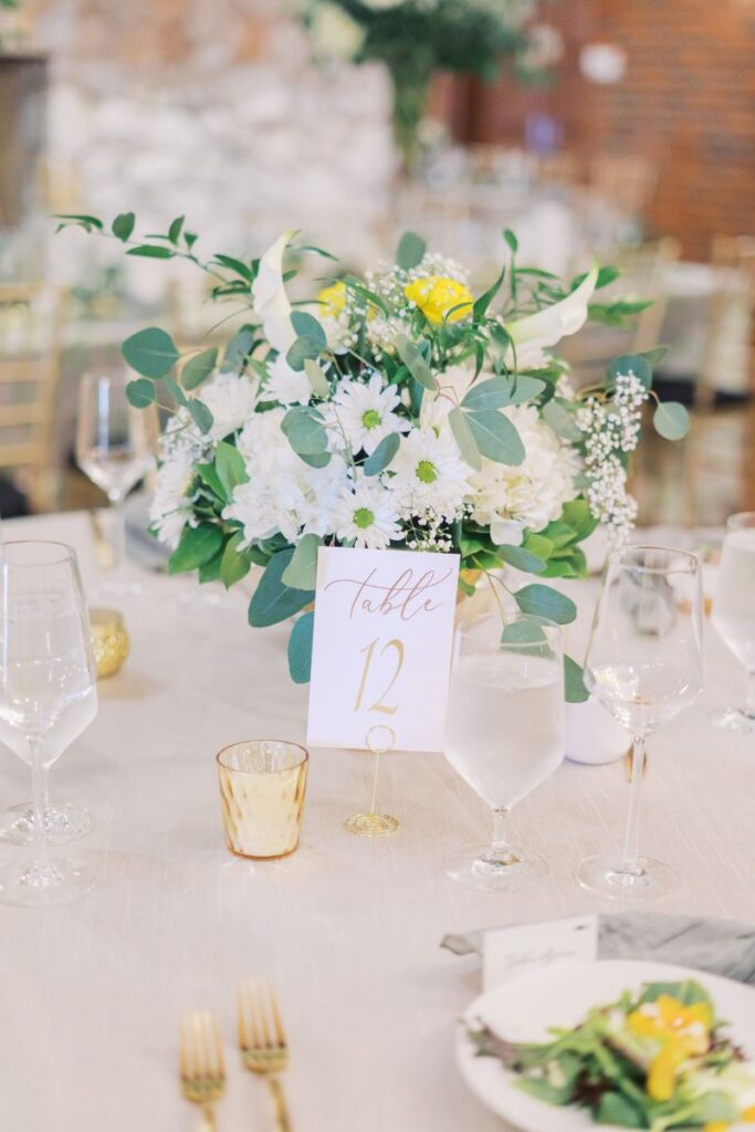 Close up photo of reception tablescape with florals and candles and the table number, highlighting details captured during wedding day coverage