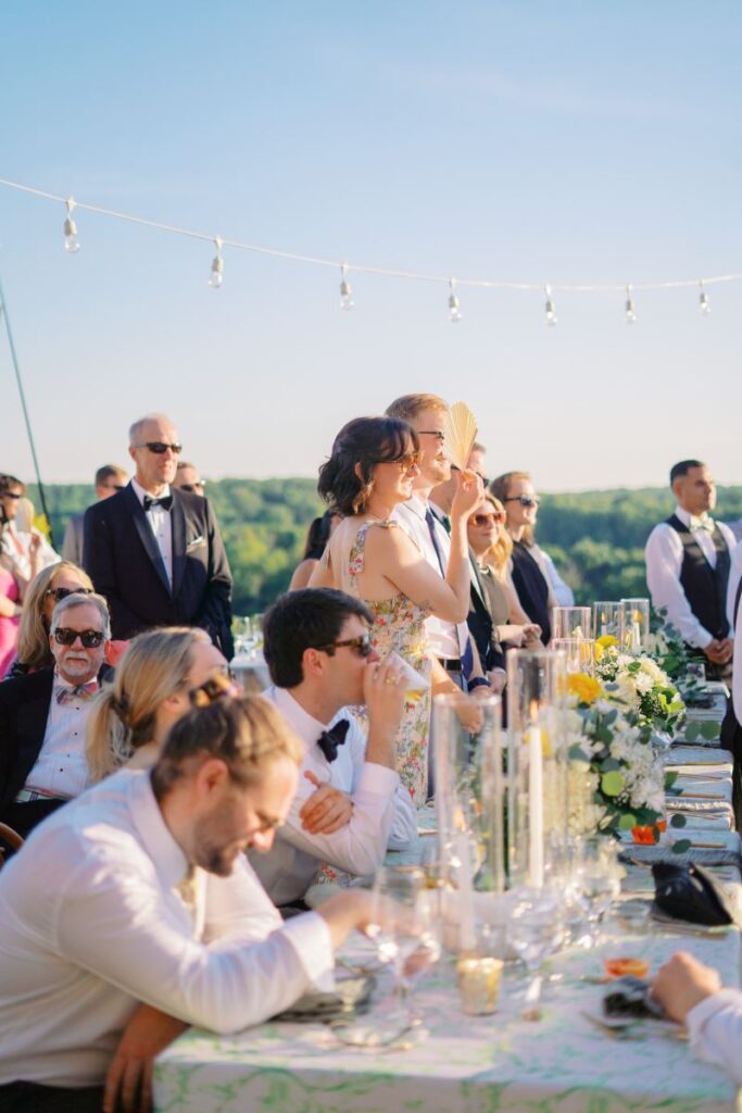 Guests laughing and reacting to toasts during an alfresco reception—candid moment captured during outdoor wedding speeches in Virginia

